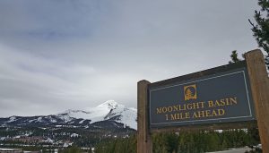 Moonlight Basin road sign with a snow covered mountain in the background