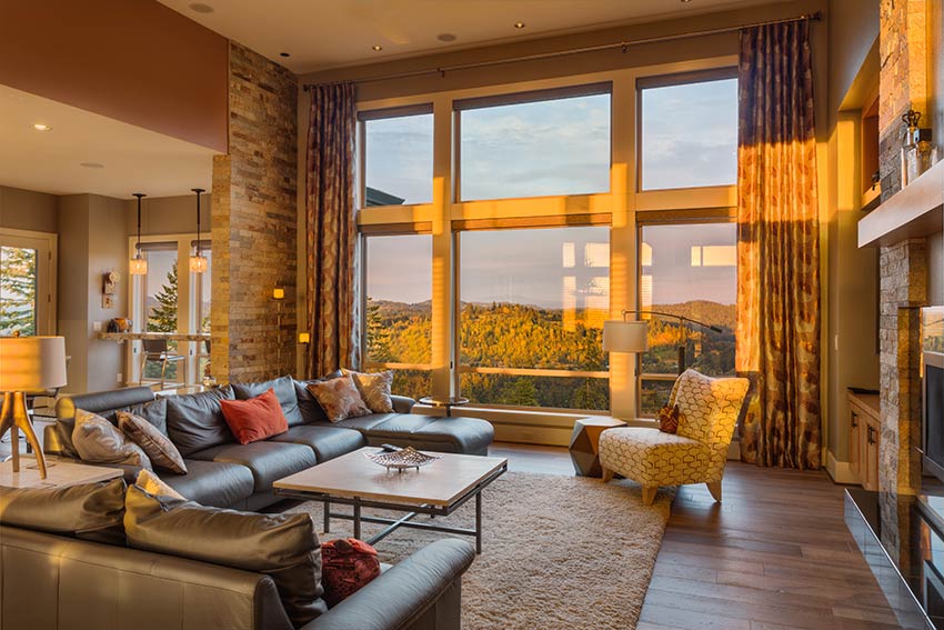 Luxury living room at sunset with plush couches and large windows