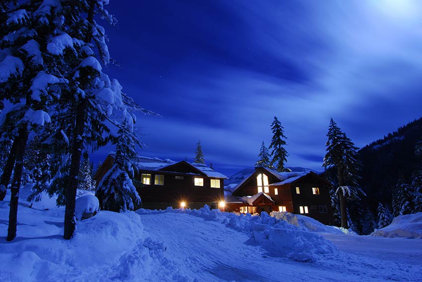 House in winter wilderness after dusk with the lights on